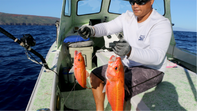 Man holding two orange fish. Click image to go to the Fishing section of the website.