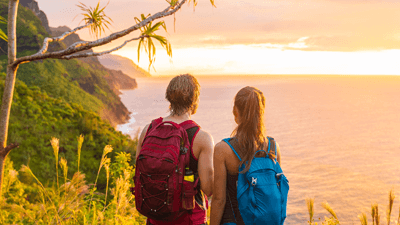 A man and woman overlook the scenic sunset while hiking.