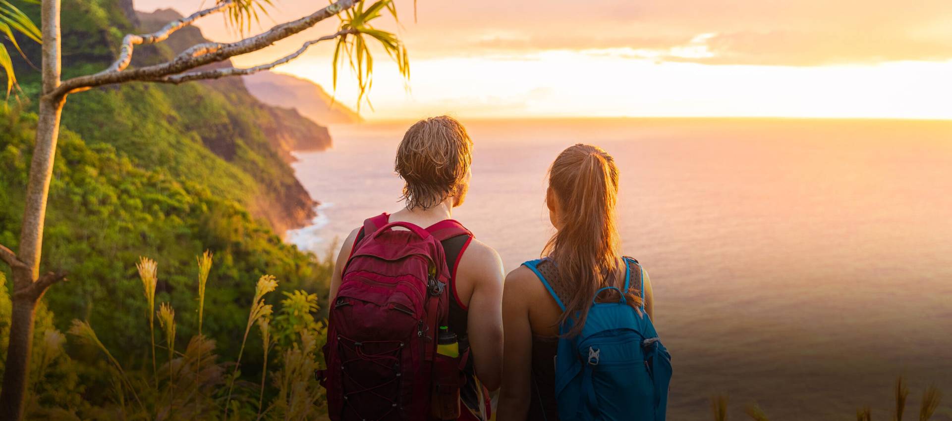 A man and woman overlook the scenic sunset while hiking.