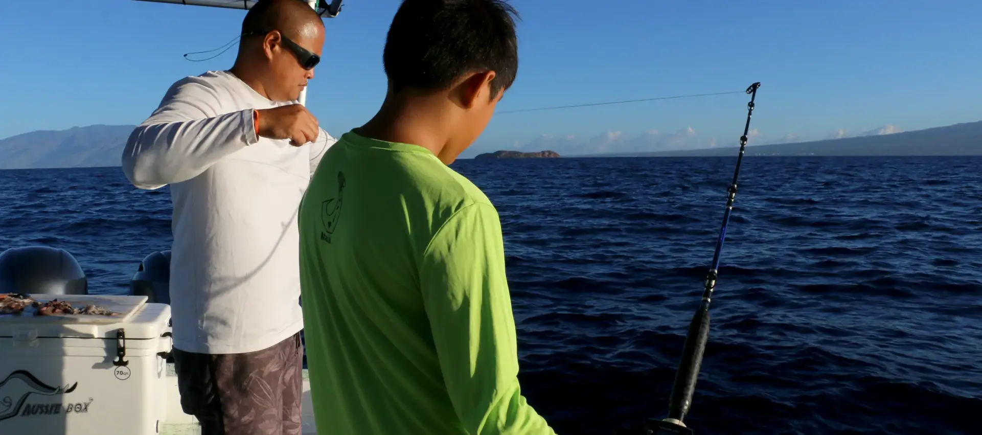 A man and boy on a charter boat getting the line ready to fish.